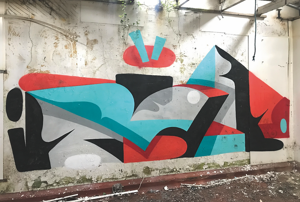Abstract graffiti mural of bold red, cyan, black shapes on a peeling white wall in an abandoned room.