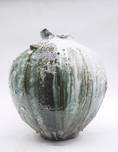 Large round ceramic vase with white and green glazed drips on a plain white background, showing an abstract, weathered look