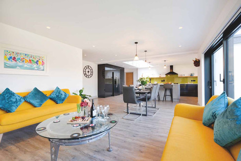 Luxury Cornish holiday home living room interior with coastal styling, soft furnishings and sea views. Stylish holiday cottage interior in Cornwall with modern kitchen island and open plan living space. Cosy coastal holiday home lounge with comfortable seating and natural light overlooking the Cornish coastline. Luxury Cornwall holiday let interior designed for families with spacious living area and coastal décor. Elegant Cornish holiday cottage bedroom with soft textiles and relaxed seaside styling. Open plan holiday home kitchen and dining space designed for entertaining during a Cornwall getaway. Family friendly holiday cottage interior in Cornwall with bright cushions, rugs and relaxed coastal styling. Cornwall holiday home terrace with outdoor seating and sea views ideal for summer evenings. Modern luxury holiday accommodation in Cornwall with stylish interiors and natural coastal colour palette. Beautiful Cornish holiday cottage exterior with landscaped garden and outdoor relaxation space.