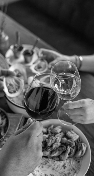 Hands clinking glasses, plates of food on a table