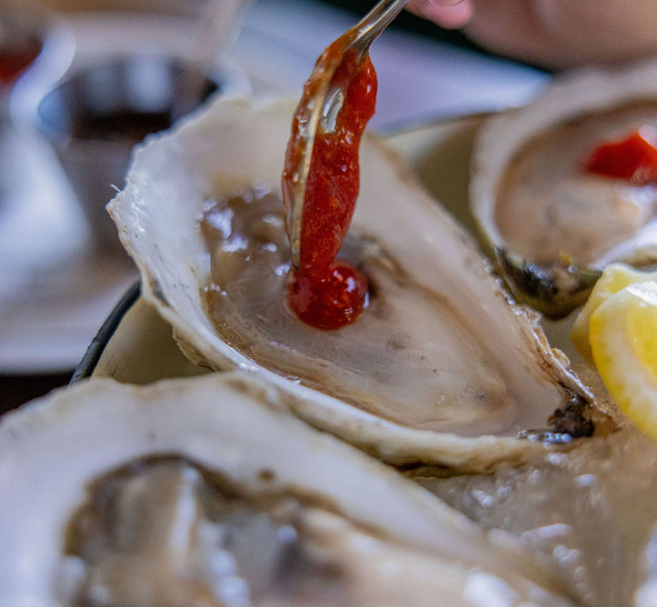Hand adding sauce to an oyster