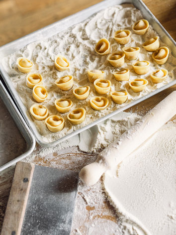 Fresh pasta, rolling pin, and flour on a wooden surface