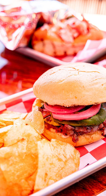 Burger with red onions, avocado, and chips