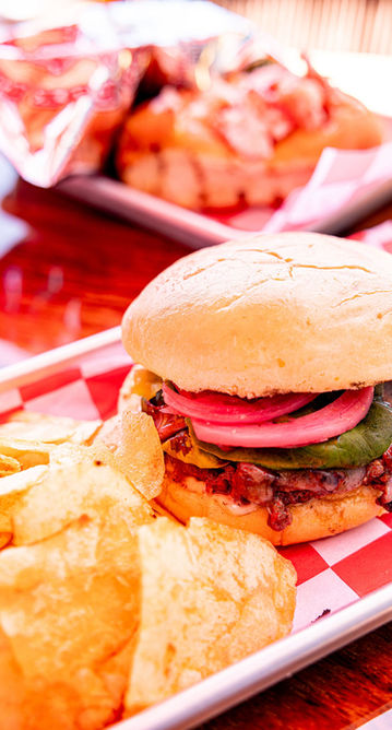 Burger with red onions, avocado, and chips