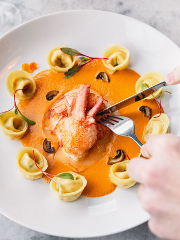Tortellini with lobster, creamy orange sauce, being cut