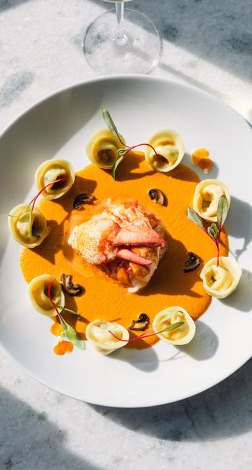 Plated lobster, tortellini, and orange sauce