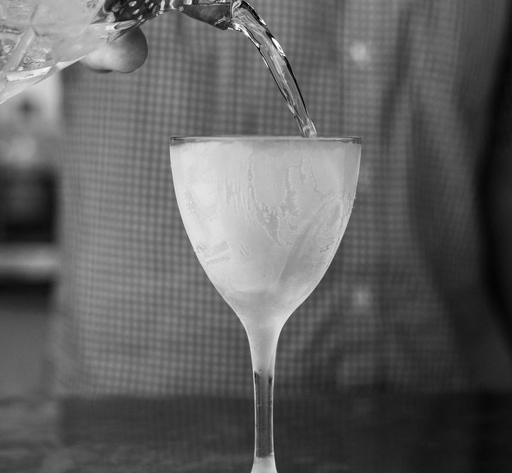 Person pouring drink into frosted coupe glass