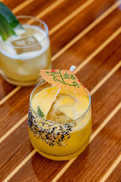 Two tropical cocktails on a wooden table