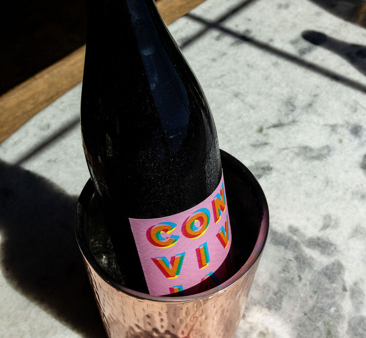 Wine bottle with colorful label in copper cooler on marble