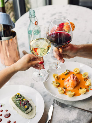 Hands toasting wine glasses over elegant dinner