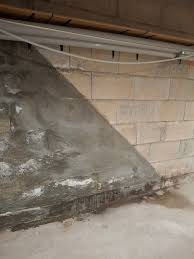 Mur en béton de sous-sol avec grosse coulée d’humidité et fissures, ambiance sombre et dégradée.