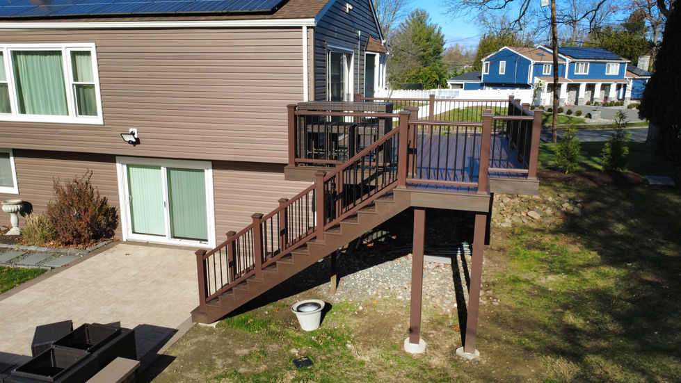“Back-left view of Wayne, NJ home featuring Trex Enhance Lava Rock deck and Rustic Blend siding.”
