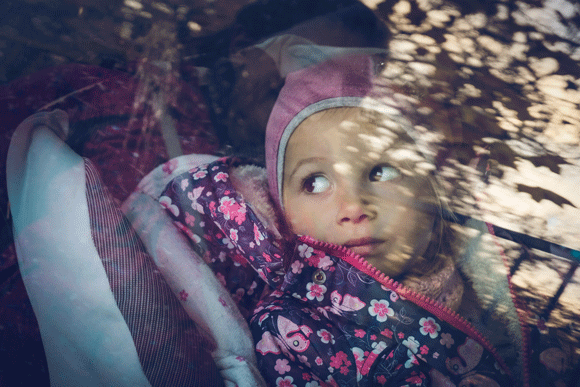 Child peers out of car window in food assistance line