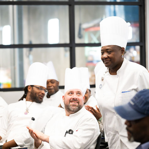 Second Harvest Providence graduates rise to receive their certificates and knife kits