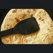 A perfectly cooked paratha being flipped with a spatula