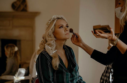 makeup artist applying Brides makeup in a softly lit room, preparing her for big day. behind the scenes bridal beauty