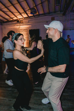 Two people dancing, holding hands, at a dance event