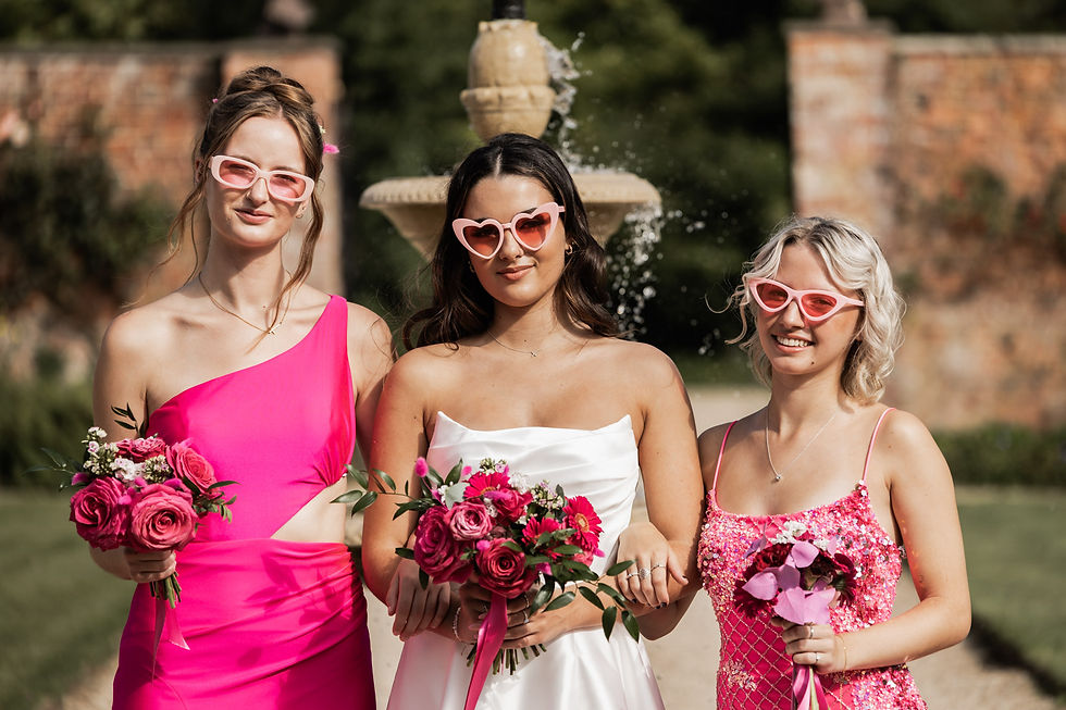 Stylish high end photo of bride and bridesmaids posing with pink heart sunglasses on a summers day wedding at Elm Hay Park Somerset.
