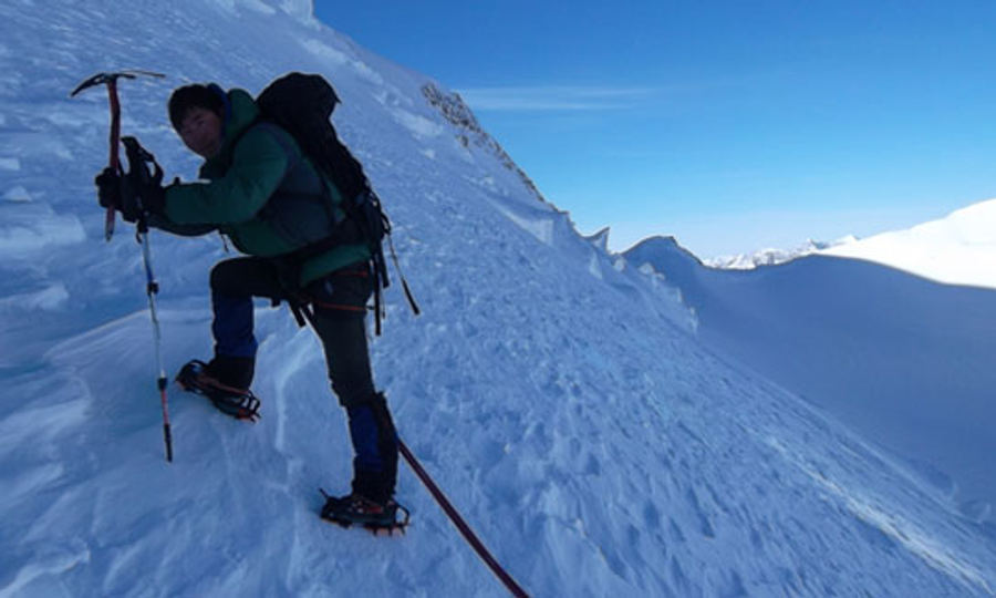 Climber with ice axe and crampons on a snow slope in Altai Tavan Bogd National Park
