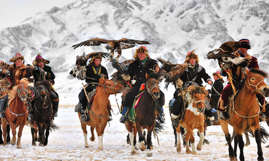 Kazakh eagle hunters on horseback holding golden eagles at the Golden Eagle Festival, Bayan-Ölgii