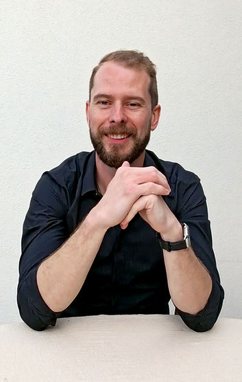 Man in black shirt holding his hands and smiling
