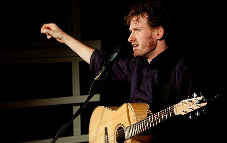 Simon Goldin chantant avec sa guitare