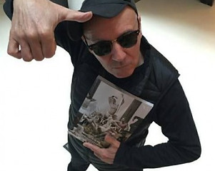 Portrait du photographe français Gérard Rancinan tenant le magazine Normal dans ses mains