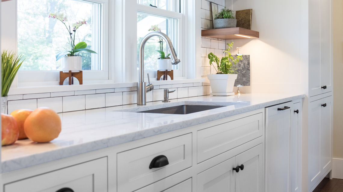 Traditional white kitchen with farmhouse details, large island, inset sink, cup pulls, bar pulls, and painted wood hood