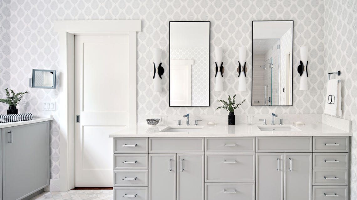 white bathroom with grey built in vanity. white and grey tones. large bathroom. black accents on sconces