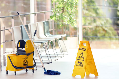 mop bucket in waiting area next to wet floor sign