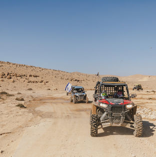 רייזר רמון | יום גיבוש בדרום | פעילות לקבוצות | שיירת רייזרים נוסעת במרחב מדברי פתוח תחת שמיים בהירים וצלולים.
