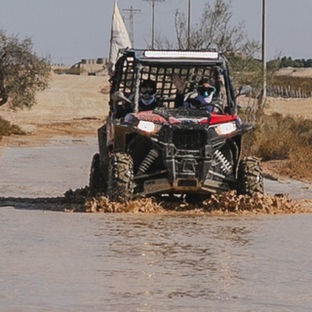רייזר רמון | אקסטרים במצפה רמון | נהיגת שטח | רייזר אדום בנסיעה חזיתית בתוך שלולית בוץ ומים עמוקה בשביל המדברי.