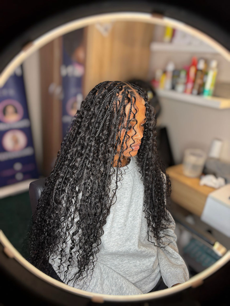 Client with long, black, small boho braids which are waist length styled by Bella Avanti