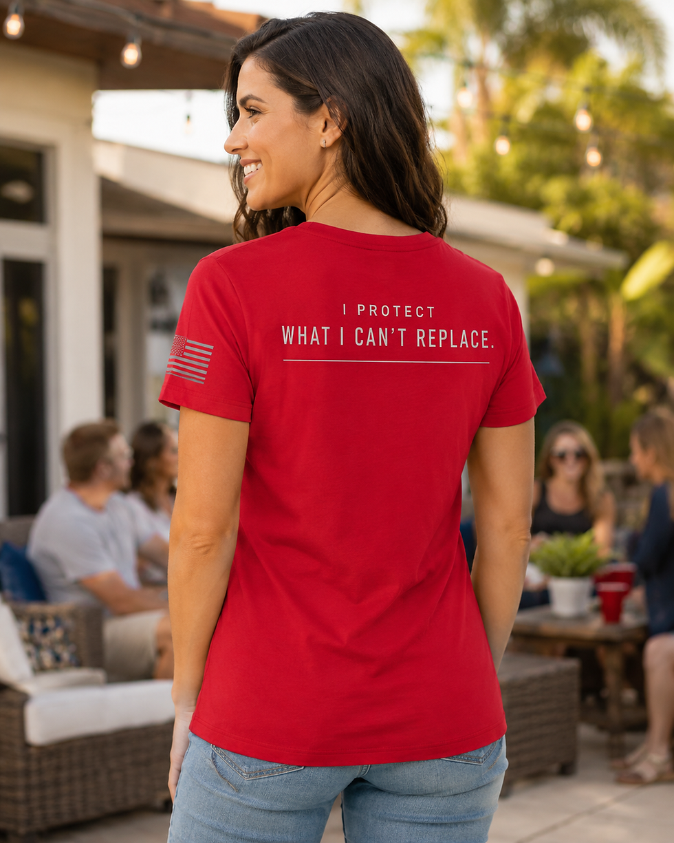 Back view of woman wearing the red I Protect What Matters V-neck tee at a community gathering