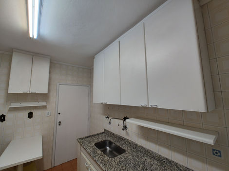 Cozinha com mobília básica e acabamento neutro, equipada com pia, armários