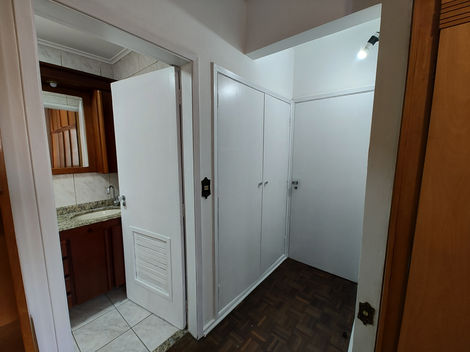 Corredor interno iluminado, com paredes brancas, piso de madeira e portas ao longo das laterais.