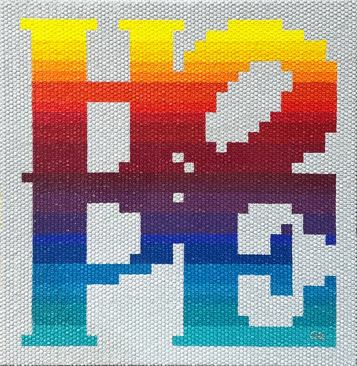 The word HOPE in rainbow gradient pixels painted on white bubble wrap.