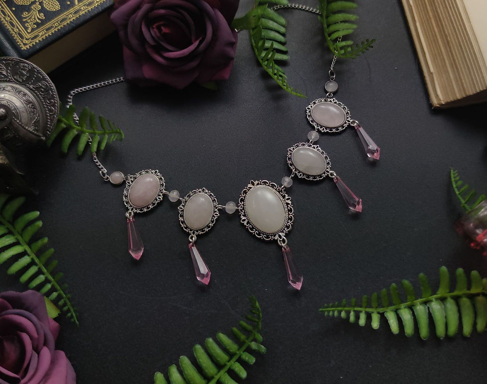 Elegante Silberkette mit rosa Steinen, Farnblättern und Rosen auf dunklem Grund.