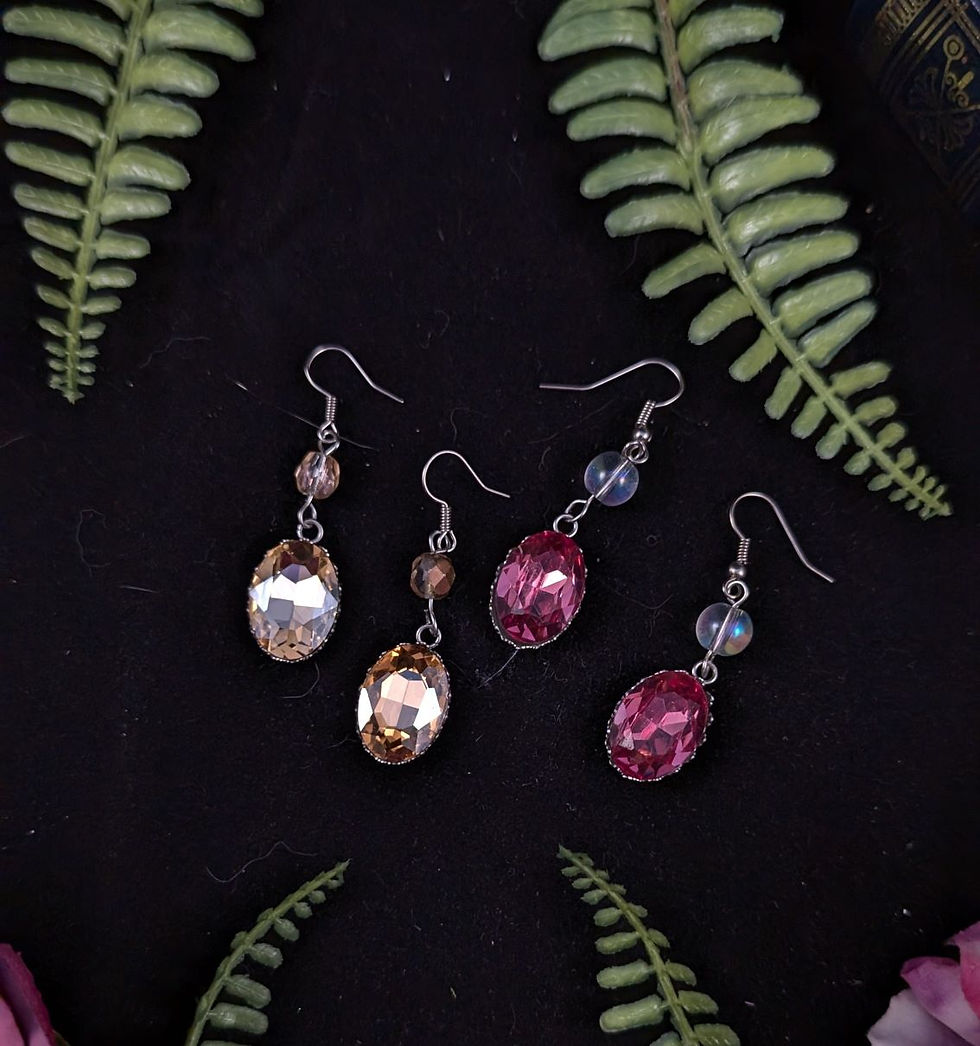 Vier Paare glitzernder Ohrringe in Champagner und Rosa auf Farnblättern.