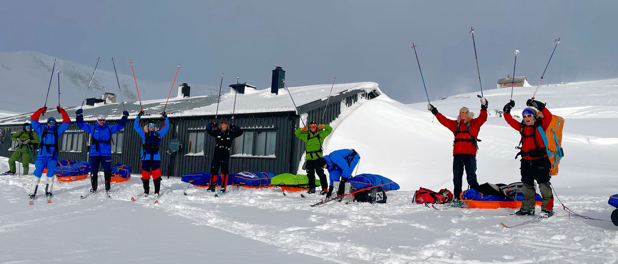 Expedition team cheering outside a snowy hut in Finse.