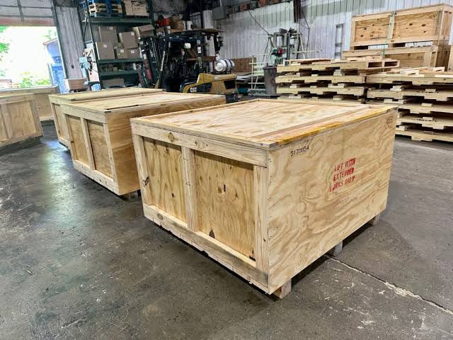 Two wooden crates sitting, Pallet Business, boxes on wheels, factory warehouse interior.