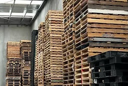 Stacked wooden pallets in a warehouse for Pallet Business, ready for shipping.