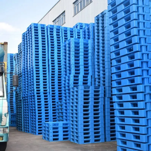 Stacked blue plastic pallets outside industrial building. Plastic Pallets in Various Settings.