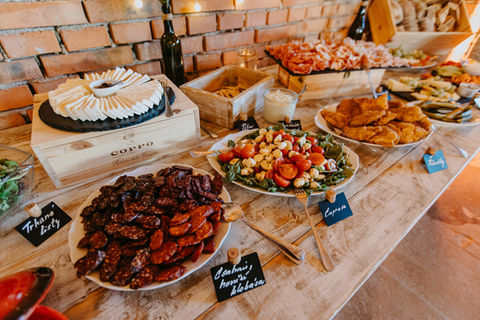 Svatební catering a bohatý raut ve Stodole v meruňkovém sadu na dřevěném stole s výběrem sýrů, uzenin a caprese salátu.