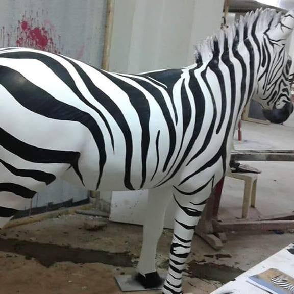 A life-size zebra statue with black and white stripes. FOAM&ART