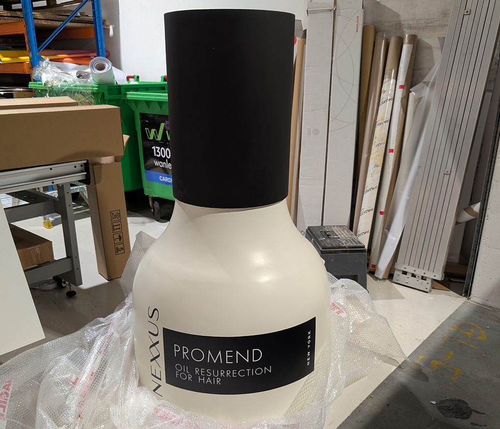 Giant NEXUS PROMEND Oil Resurrection for Hair bottle stands in a cluttered workshop, wrapped in bubble plastic.