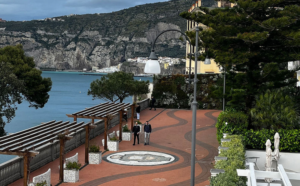 Two people on a leisure hiking tour walking down a path near the water.