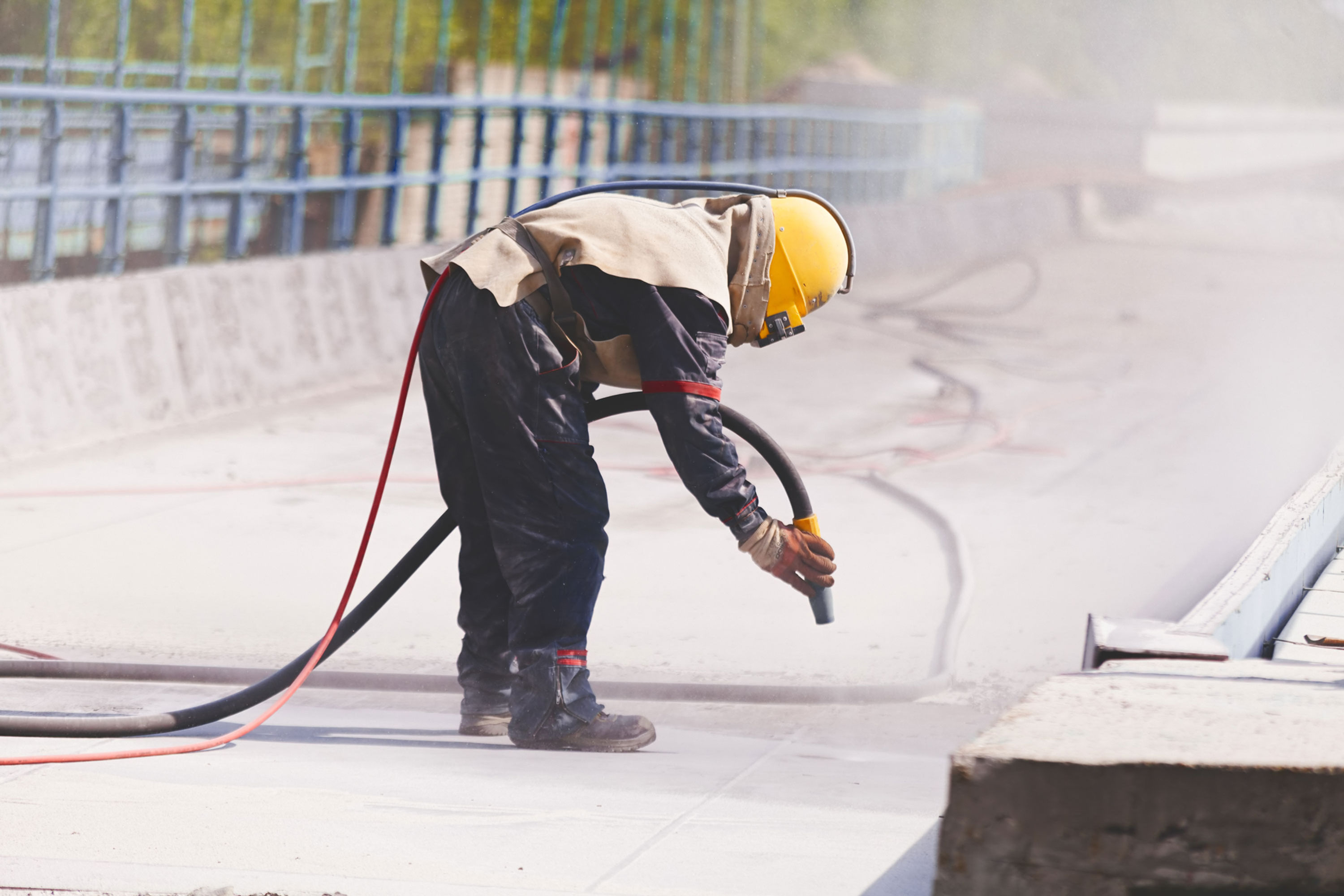 Worker in protective gear sandblasting concrete surface for construction project Lightweight Concrete