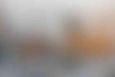 sala de estar com sofá cinza, poltronas em couro e detalhes em laranja e preto