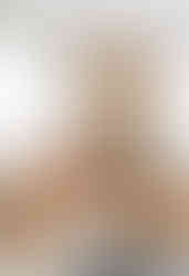 sala de estar redonda com sofás e poltronas claras, lareira revestida em pedra e objetos em tons de terracota